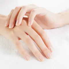 Dłonie z zadbanymi, naturalnymi paznokciami na białym tle.