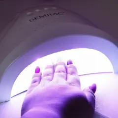 Dłoń z paznokciami hybrydowymi w lampie UV marki Semilac.