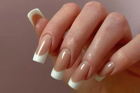 Dłoń z perfekcyjnym manicure hybrydowym w stylu francuskim.