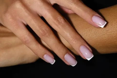 Dłonie z klasycznym french manicure – różowe paznokcie z białymi końcówkami.