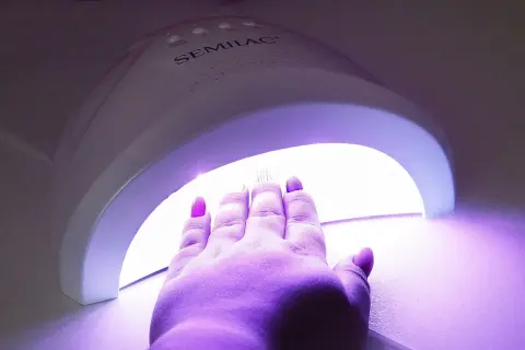 Dłoń z paznokciami hybrydowymi w lampie UV marki Semilac.