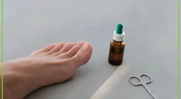 Stopa z widocznymi paznokciami, buteleczka z kroplomierzem i małe nożyczki.