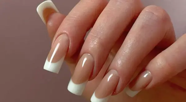 Dłoń z perfekcyjnym manicure hybrydowym w stylu francuskim.