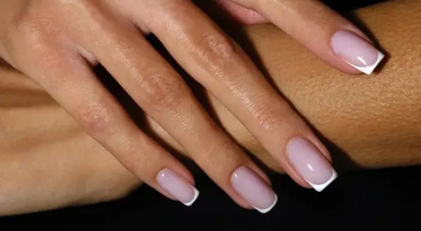Dłonie z klasycznym french manicure – różowe paznokcie z białymi końcówkami.