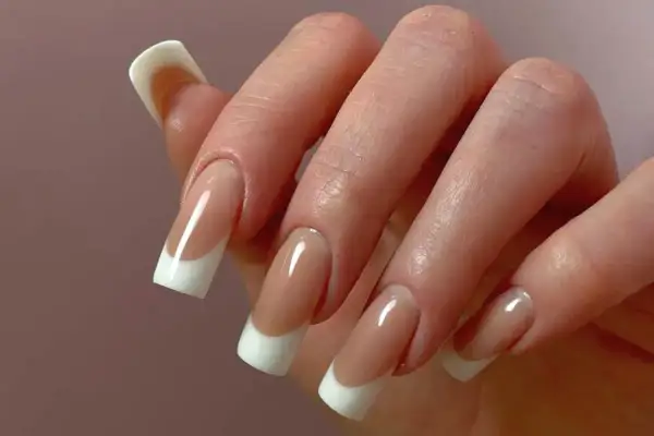 Dłoń z perfekcyjnym manicure hybrydowym w stylu francuskim.