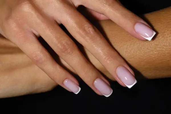 Dłonie z klasycznym french manicure – różowe paznokcie z białymi końcówkami.